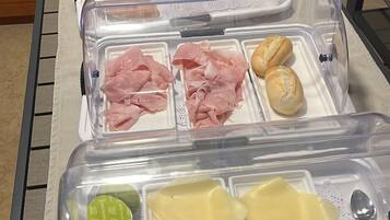 Una mesa de buffet con diversos alimentos en recipientes transparentes.