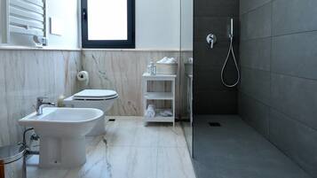 A modern bathroom with a bidet, toilet, and walk-in shower.