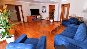 A living room with a sofa set, a coffee table, a TV, and a bookshelf. - Le Cinèma (Formia)