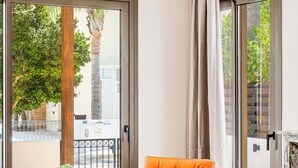 A modern living room with a glass table, a leather armchair, and a view of the outdoors through large sliding doors.