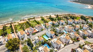 A coastal residential area with white buildings, a swimming pool, and a beach.