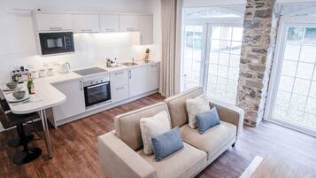 Una cocina moderna con armarios blancos, microondas integrado y un comedor con mesa y sillas.