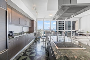 A modern kitchen with a dining area, large windows, and a city view.