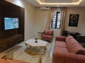 A modern living room with a flat-screen TV, a sofa, a coffee table, and a decorative vase. - Hotel Marmaris oweri (Owerri)