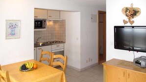 Un espai vital reduït amb cuina, zona de menjador i televisió.