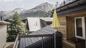 A mountain view with a wooden building and a yellow umbrella.