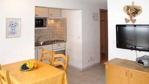 A compact living space with a dining area, kitchenette, and a television.