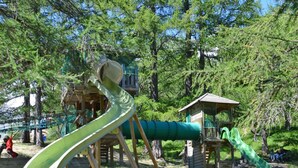 A playground with a green slide and climbing structures.