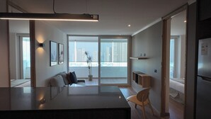 Una cocina moderna con una isla grande, un rincón de comedor con un sofá y vistas de la ciudad a través de amplios ventanales.