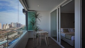 Un balcón con mesa y sillas, una cama y vistas de la ciudad.