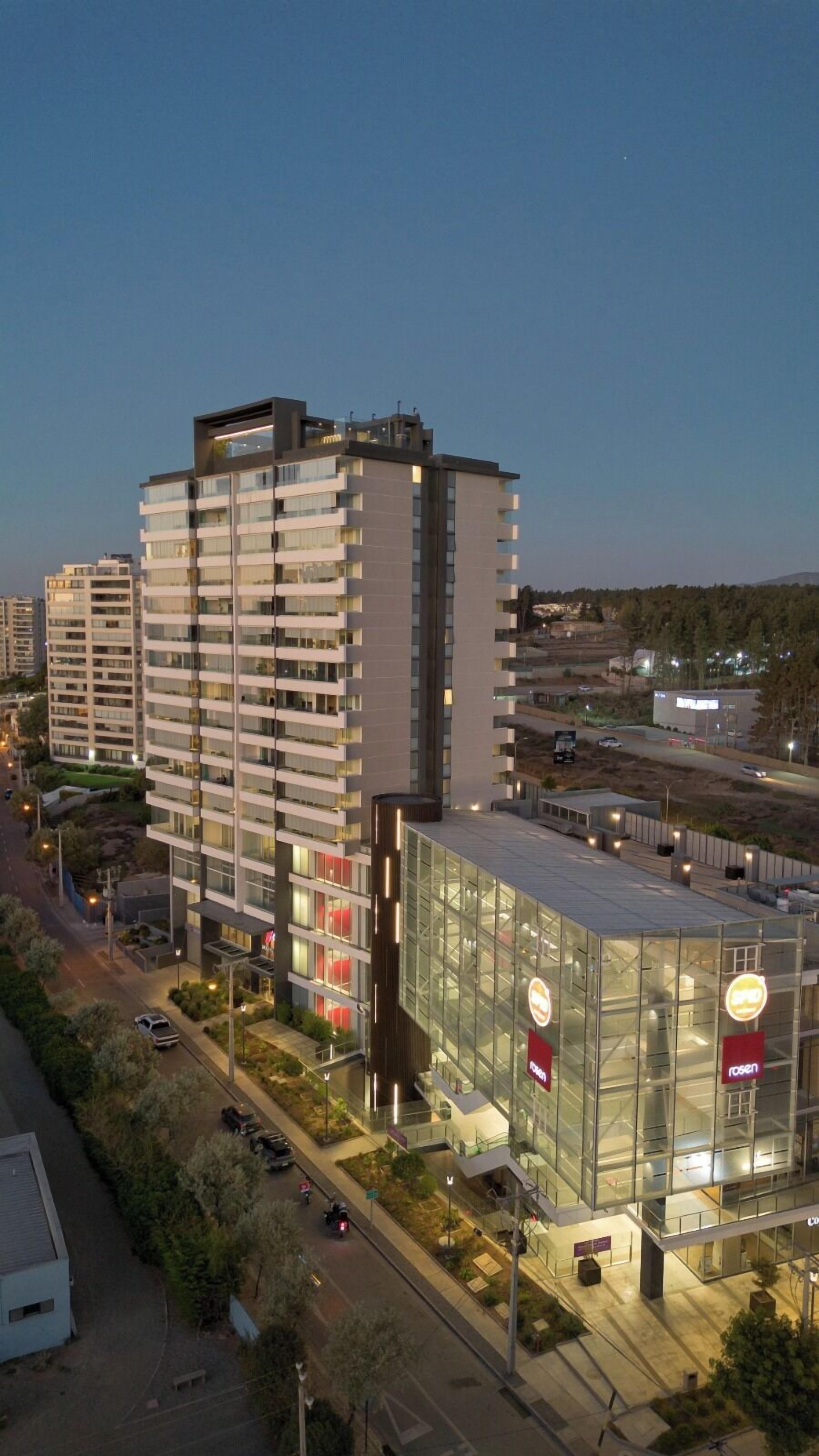 A modern multi-story hotel with a glass facade, a rooftop terrace, and a visible restaurant sign.
