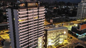 Un hotel moderno de gran altura con varias plantas, fachada de vidrio y un área de entrada bien iluminada.