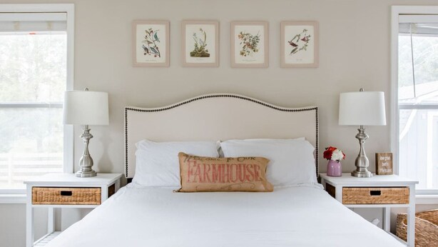 Un dormitorio con una cama, dos mesitas de noche, un cabecero y una obra de arte en la pared.