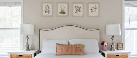 Un dormitorio con cama, dos mesitas de noche, cabecero y una obra de arte en la pared.