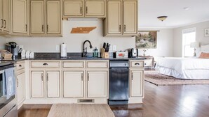 Cozinha com armários bege, lava-louças e bancada com diversos eletrodomésticos e utensílios.