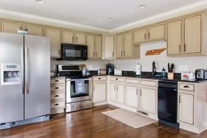 Une cuisine moderne dotée d’appareils électroménagers en acier inoxydable, de meubles de couleur beige et d’un plancher en bois.