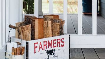 A wooden crate labeled "FARMERS" with wood logs and a "welcome" sign on a porch.