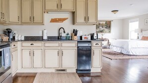 Una cocina con armarios color beige, lavavajillas y una encimera con diversos electrodomésticos y utensilios.