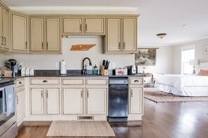 A kitchen with beige cabinetry, a dishwasher, and a countertop with various appliances and utensils. - The Franklin Farmhouse of Franklin, TN (Franklin)