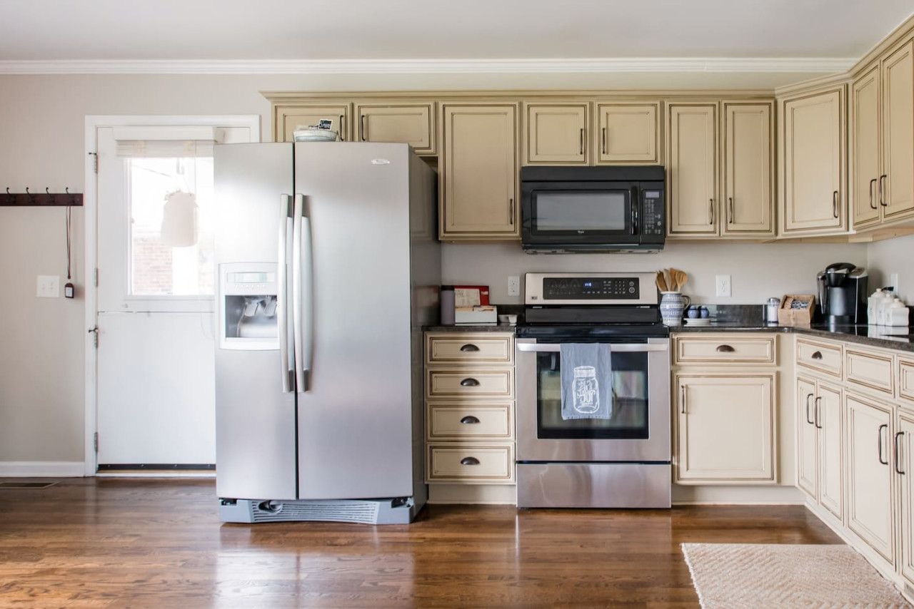 A kitchen with a refrigerator, microwave, oven, and cabinets.