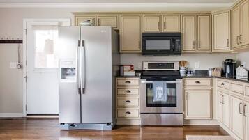 A kitchen with a refrigerator, microwave, oven, and cabinets.