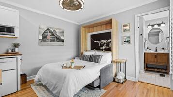 A bedroom with a bed, bedside table, lamp, and artwork.
