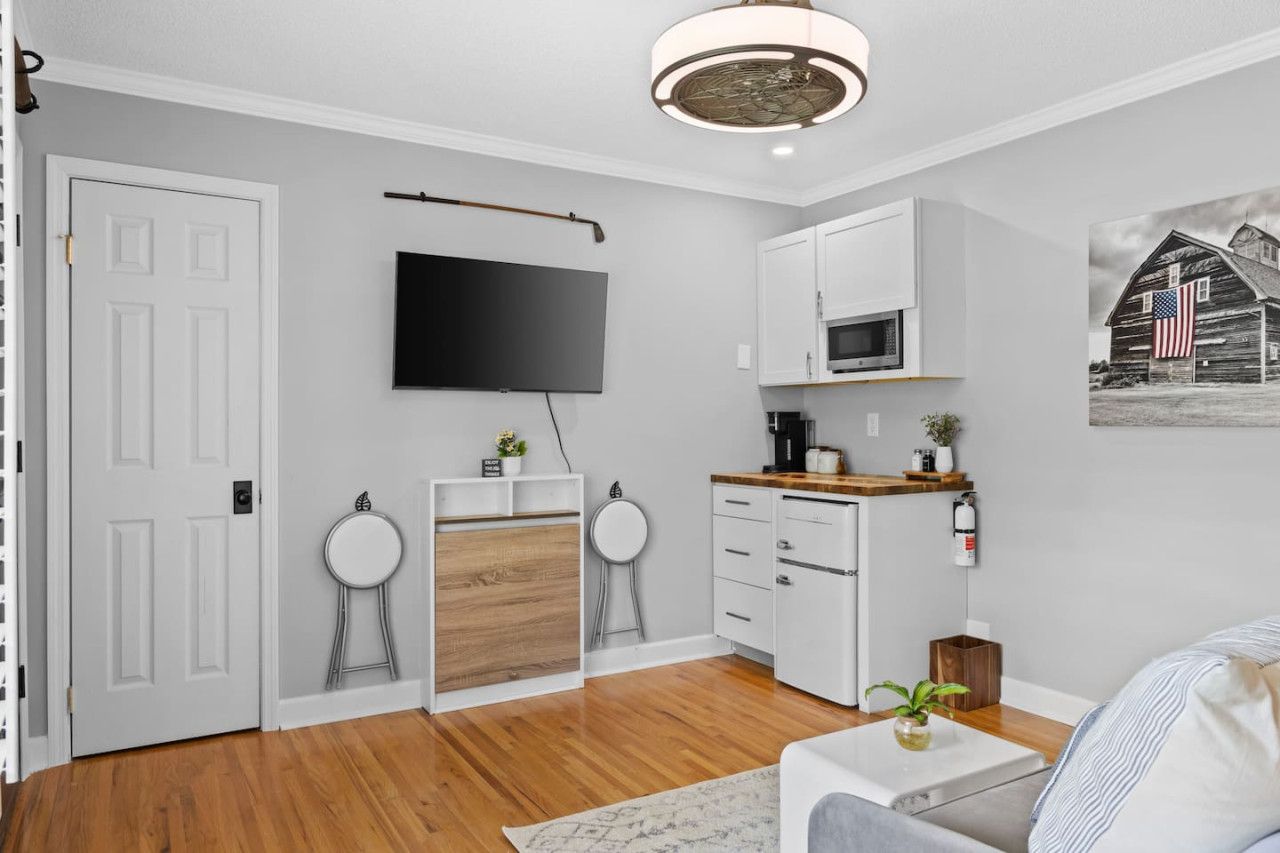 A compact living space with a kitchenette, a flat-screen TV, and a small dining area.