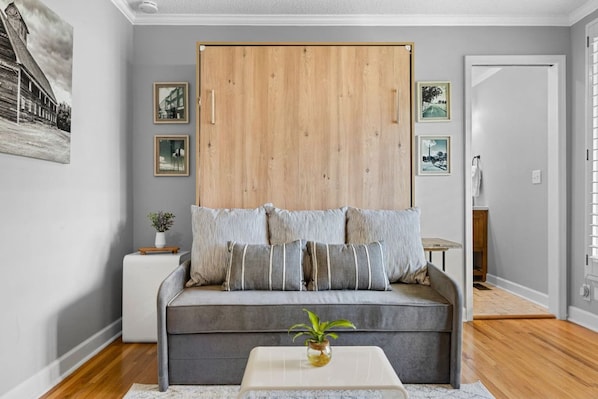 Un salón moderno con un sofá gris, un armario de madera y cuadros enmarcados en la pared.