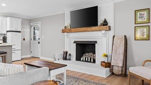 Una sala de estar moderna con chimenea, un televisor montado encima y un rincón de estar acogedor.