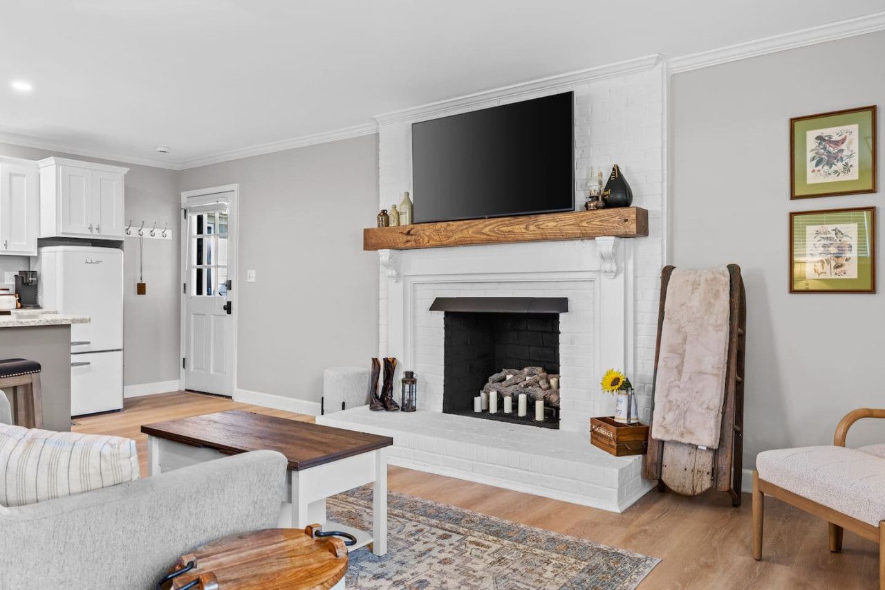 A modern living room with a fireplace, a flat-screen TV mounted above it, and a cozy seating area with a coffee table.