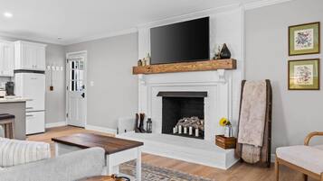 A modern living room with a fireplace, a flat-screen TV mounted above it, and a cozy seating area with a coffee table.