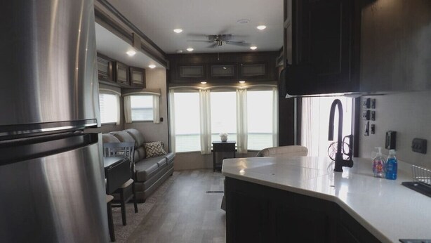 A modern kitchen with a large refrigerator, a dining area with a sofa, and a view of the outdoors through large windows. - The Castle at Rock Castle (Cadiz)