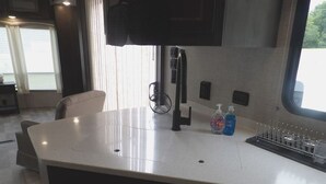 A kitchen with a white countertop, a black chair, a window, and a sink. - The Castle at Rock Castle (Cadiz)