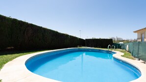 A circular swimming pool with a clear blue water surface, surrounded by a light-colored deck.