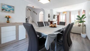 A modern dining area with a rectangular table, black chairs, and a central light fixture.