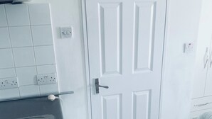Une salle de bain avec une porte blanche, un lavabo noir et un sol carrelé.