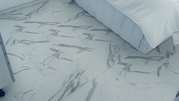 Une chambre à coucher comprenant un lit, une armoire et un sol à motifs de marbre.