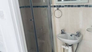 Une salle de bain avec une douche à parois de verre, un lavabo avec un miroir au-dessus et des toilettes.