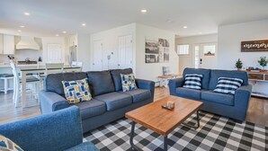 Ein modernes Wohnzimmer mit zwei Sofas, einem Holztisch und einem karierten Teppich.