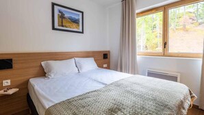 A hotel room with a bed, a framed picture on the wall, a window with curtains, and a wooden headboard. - Wifi, 80m from ski slopes, balcony, tv, ski locker, 37-39m², Vars (Vars)