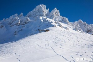 Ein schneebedeckter Berg mit Skipisten und blauem Himmel.