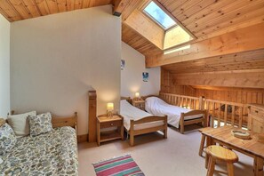 Une chambre confortable dans un chalet, avec deux lits en bois, une petite table et un canapé.