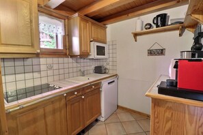 A compact kitchen with wooden cabinets, a microwave, a sink, and a dishwasher.