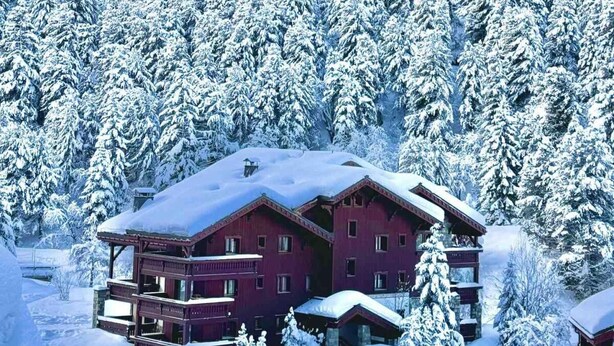 A red building with multiple balconies, surrounded by snow-covered trees and a mountain in the background. - 200m from ski slopes, 2nd floor, terrace, fireplace or stove, ski locker, 62m², Méribel-Mottaret (Méribel - Les Allues)