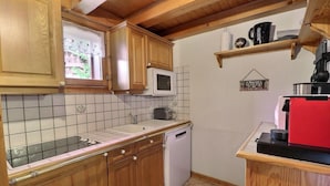 A compact kitchen with wooden cabinets, a microwave, a sink, and a red coffee machine. - 200m from ski slopes, 2nd floor, terrace, fireplace or stove, ski locker, 62m², Méribel-Mottaret (Méribel - Les Allues)