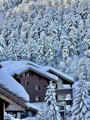 A snow-covered lodge with a stone facade, multiple windows, and a wooden roof. - 200m from ski slopes, 2nd floor, terrace, fireplace or stove, ski locker, 62m², Méribel-Mottaret (Méribel - Les Allues)