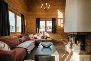 A cozy log cabin interior with a fireplace, wooden walls, and a sofa.