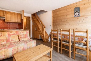 A cozy room with a wooden staircase, a sofa, a wooden table, and a bed with patterned bedding.