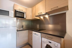 A compact kitchen with a microwave, oven, sink, dishwasher, and washing machine.