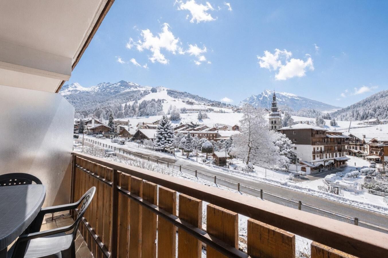 A balcony with a view of a snow-covered village and mountains.